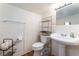 Clean bathroom with white tile, toilet, sink, mirror, and a metal shelving unit for storage at 1615 Palora Ave, Las Vegas, NV 89169
