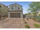 Inviting two-story home with a brick driveway, desert landscaping, and an attached garage at 169 Volti Subito Way, Henderson, NV 89011