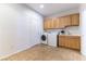 Well-lit laundry room featuring tile floors, washer, dryer, sink, and wooden cabinets at 2357 Aztec Ruin Way, Henderson, NV 89044