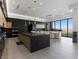 Modern kitchen features sleek black and wood cabinetry, expansive island, and stunning city views at 25 Rockstream Dr, Henderson, NV 89012