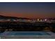 Inviting pool area with stunning views of the city skyline at twilight; relax in style at 25 Rockstream Dr, Henderson, NV 89012