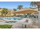 Community pool with lounge chairs, tables, umbrellas, and palm trees at 3924 Quiet Pine St # 201, Las Vegas, NV 89108