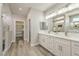 Bathroom featuring double sinks, quartz counters, wood-look floors, and a walk-in shower with marble tile at 5251 Graystone, Pahrump, NV 89061