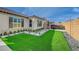 Serene backyard featuring manicured artificial turf, stone pavers, lush landscaping, and a luxurious hot tub at 6544 Sandero Springs St, Las Vegas, NV 89166
