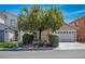 Inviting two-story home with manicured front yard, tree, lush landscaping, and a two-car garage at 7572 Hope Valley St, Las Vegas, NV 89139