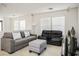 Comfortable living room featuring two sofas, an ottoman, and ample natural light through bright windows at 7572 Hope Valley St, Las Vegas, NV 89139
