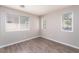 Bright bedroom with multiple windows, neutral walls, and stylish gray wood-look flooring at 8174 Amphora St, Las Vegas, NV 89139