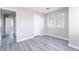 Sunlit bedroom with a large window, neutral walls, and stylish gray wood-look flooring at 8174 Amphora St, Las Vegas, NV 89139
