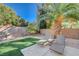 Landscaped backyard featuring a patio with lounge chairs, artificial turf and mature palm trees at 8962 Shale Valley St, Las Vegas, NV 89123