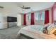 Spacious main bedroom featuring carpet, ceiling fan, dresser, and large windows with red curtains at 9020 Tiffany Oaks Ave, Las Vegas, NV 89148