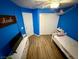 Blue bedroom featuring a white bed, wood-look flooring, and a decorative wall hammock at 10271 Headrick Dr, Las Vegas, NV 89166