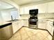Bright kitchen features stainless steel appliances, white cabinets, and tile flooring at 10372 Beautiful Fruit St, Las Vegas, NV 89183