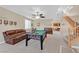 Spacious living room features a billiard table, a comfortable leather couch, and staircase to second floor at 10409 Snowdon Flat Ct, Las Vegas, NV 89129