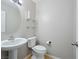 Clean half-bathroom featuring a white sink, toilet, and decorative mirrored shelving at 10609 Sand Mountain Ave, Las Vegas, NV 89166