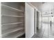 Hallway featuring gray tiled floor, white shelving, and leads to an open, bright room with large windows at 1400 Jamielinn Ln # 104, Las Vegas, NV 89110