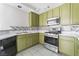 Modern kitchen with stainless steel appliances, tiled backsplash, marble countertops, and green cabinetry at 1400 Jamielinn Ln # 104, Las Vegas, NV 89110