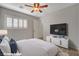 Comfortable bedroom featuring a ceiling fan, window with shutters, and a wall-mounted television at 165 Calm Morning Ave, Henderson, NV 89002