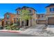 Charming two-story stucco home with a landscaped front yard and a spacious driveway on a sunny day at 165 Calm Morning Ave, Henderson, NV 89002