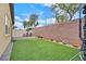 Lush backyard with artificial grass, brick wall, patio furniture, and potted plants at 2104 Leatherbridge Ct, North Las Vegas, NV 89081