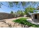 Private backyard features synthetic grass, mature trees, and privacy wall at 212 View Dr, Las Vegas, NV 89107