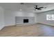 Bright living room featuring a ceiling fan and a painted white brick fireplace, enhanced by wood-look flooring at 212 View Dr, Las Vegas, NV 89107