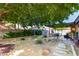 Landscaped backyard with a patio area, garden beds, and mature trees providing shade at 3138 Valleywood Rd, Henderson, NV 89014