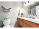 Bathroom featuring white toilet, wood cabinets with white countertop, large mirror, and a shower with curtain at 3138 Valleywood Rd, Henderson, NV 89014