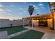 A backyard with grass, stone pavers, and a covered patio with a foosball table and string lights at 5208 Overland Ave, Las Vegas, NV 89107