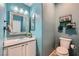 Powder room featuring bright blue walls, modern floating shelves, and a white toilet and vanity at 5853 Gentleslope St, Henderson, NV 89011