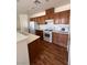 Kitchen area with wood-style flooring, white appliances, wooden cabinets, and bright white countertops at 6158 Calm Breeze Ave # 101, Las Vegas, NV 89108