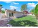 Spacious backyard with well-kept lawn, mature trees, and partial view of house with sliding glass door at 6408 Shawnee Pl, Las Vegas, NV 89107