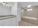 Bright bathroom featuring a dual-sink vanity with granite countertop and a tiled bathtub with shower at 6408 Shawnee Pl, Las Vegas, NV 89107