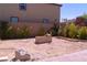 Wide backyard shot shows the dirt yard plus a block fire pit, and perimeter plants ready for customization at 6631 Frosted Harvest Ave, Las Vegas, NV 89108