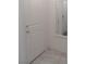 Hallway with a white door and gray ceramic tile flooring, adjacent to a mirror on the wall at 6631 Frosted Harvest Ave, Las Vegas, NV 89108