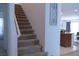Carpeted staircase with bright white walls, a modern art piece, and open access to the kitchen at 6631 Frosted Harvest Ave, Las Vegas, NV 89108