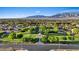 Aerial view of a green neighborhood park surrounded by mature trees, houses, and a mountain range at 6907 Kelp Ledge Ct, Las Vegas, NV 89131