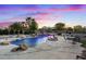 An inground pool with rock waterfall feature and patio seating under a dramatic twilight sky at 6907 Kelp Ledge Ct, Las Vegas, NV 89131