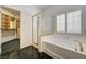 Bright bathroom featuring a glass-enclosed shower, soaking tub, shuttered window, and a closet view at 900 Royal Plum Ln, Las Vegas, NV 89144