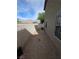 Narrow gravel side yard features a brick wall, access to the back, and compact space for utility equipment at 1144 Black Cherry St, Las Vegas, NV 89142