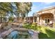 Scenic backyard view featuring a serene pond, lush lawn, mature trees, and covered patio, creating a peaceful retreat at 1234 Campbell Dr, Las Vegas, NV 89102