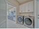 Laundry room featuring a washer and dryer, with built-in white cabinets and a glimpse of the kitchen at 2171 Deadwood St, Pahrump, NV 89048