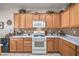 Functional kitchen with wooden cabinets, white appliances, tile backsplash, and countertops at 2539 Stardust Valley Dr, Henderson, NV 89044