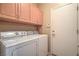 Functional laundry room featuring a white washer and dryer, storage cabinets, and access door at 2539 Stardust Valley Dr, Henderson, NV 89044