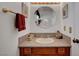 Powder room with wooden cabinets, granite countertops, round mirror, and brushed gold hardware at 3380 Pavlo St, Las Vegas, NV 89121
