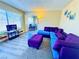 Bright living room with gray floors, blue and purple sofa set, and large sunny window at 4016 Calle Paula, Las Vegas, NV 89103