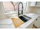 Modern kitchen sink with sleek faucet, wooden cutting board, and stylish countertop by the window at 5345 Tustin Hills St, North Las Vegas, NV 89081