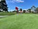 View of the golf course with a red flag on the green and a beautiful home in the background at 5436 Red Sun Dr, Las Vegas, NV 89149