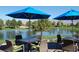 Charming outdoor patio with scenic views of the pond, complete with tables, chairs, and blue umbrellas at 5500 E Volterra Dr, Pahrump, NV 89061