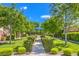 Beautifully landscaped walking path featuring lush greenery, mature trees, and a covered seating area at 5500 E Volterra Dr, Pahrump, NV 89061