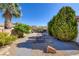 Landscaped front yard featuring a palm tree, gravel ground cover, lush green bushes, and rock accents at 5858 Majestic Tide Ave, Las Vegas, NV 89131